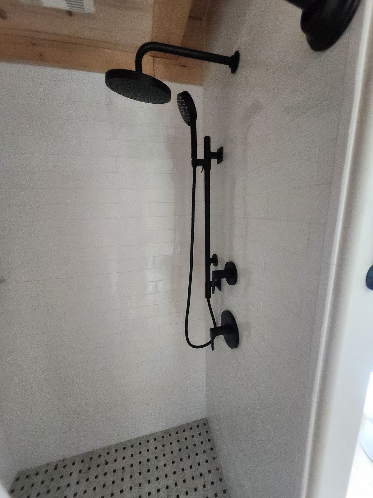 Matte black rain head and slide-bar hand shower in a white tile shower