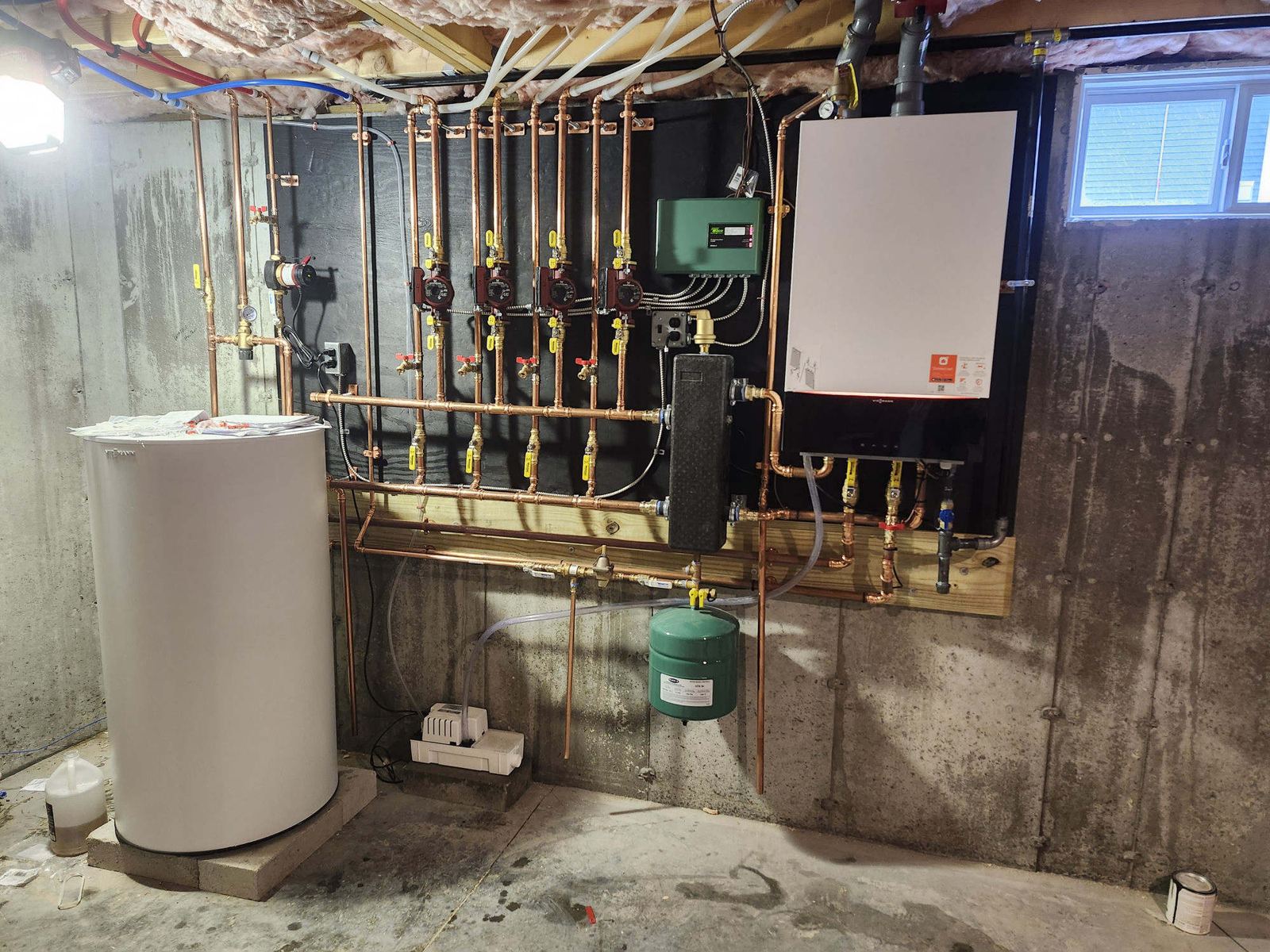 Wall-hung boiler, indirect water heater, and copper zone manifold in a basement mechanical room
