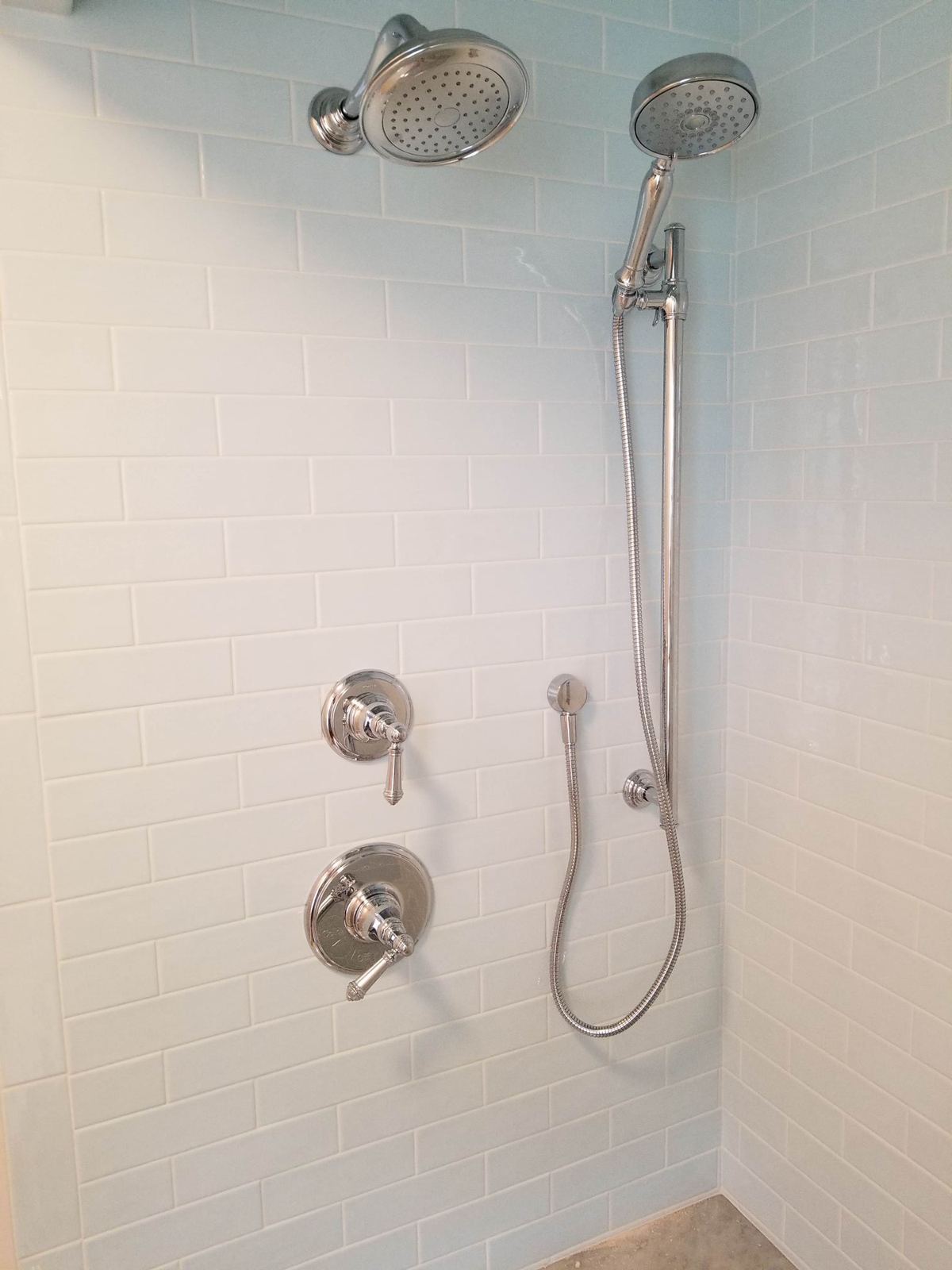 Tiled shower with chrome rain head and slide-bar hand shower