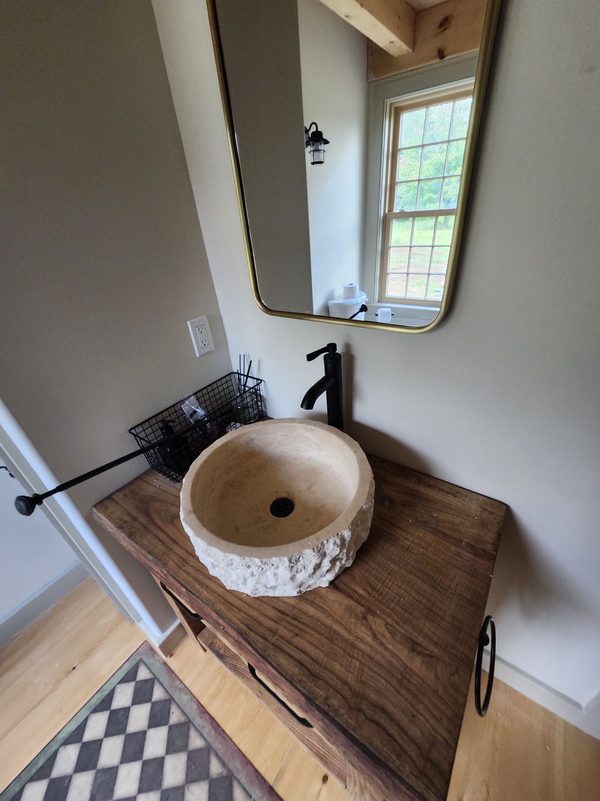 Carved stone vessel sink with matte black faucet on a live-edge wood vanity